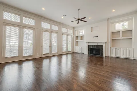 an empty room with wooden floor fireplace and windows