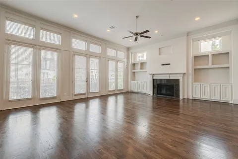 an empty room with wooden floor fireplace and windows