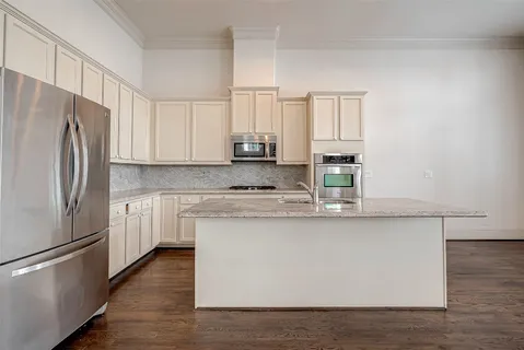 a kitchen with stainless steel appliances granite countertop a refrigerator a stove a sink and white countertops with wooden floor