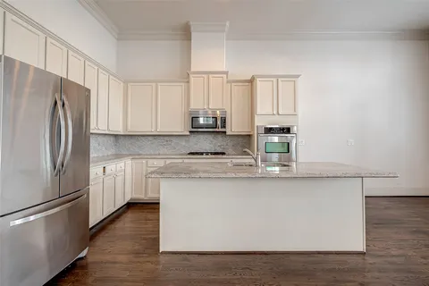 a kitchen with stainless steel appliances granite countertop a refrigerator a stove a sink and white countertops with wooden floor