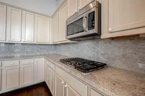 a kitchen with granite countertop white cabinets and stainless steel appliances