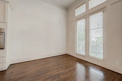 an empty room with wooden floor and windows with curtains