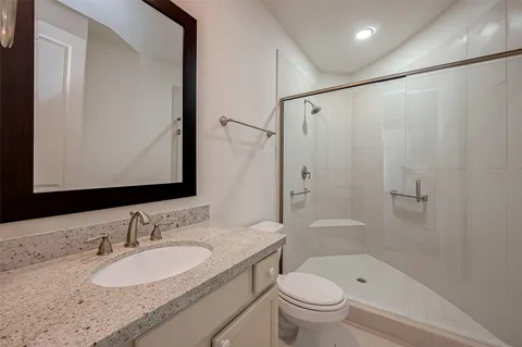 a bathroom with a granite countertop sink toilet and shower