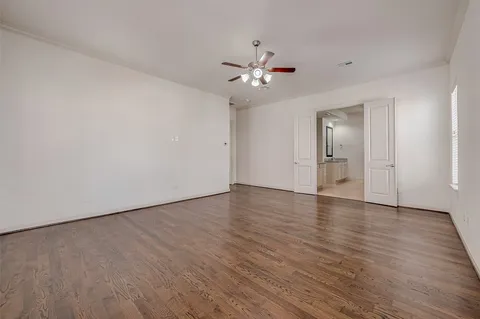 an empty room with wooden floor fan and windows