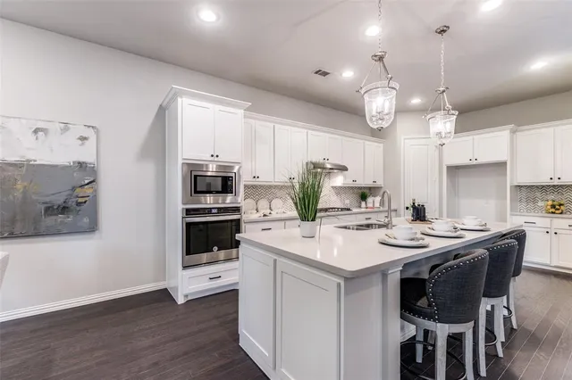 a kitchen that has a lot of cabinets a sink and appliances