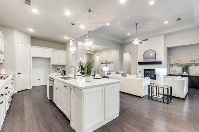 a large white kitchen with lots of counter space a sink appliances and cabinets