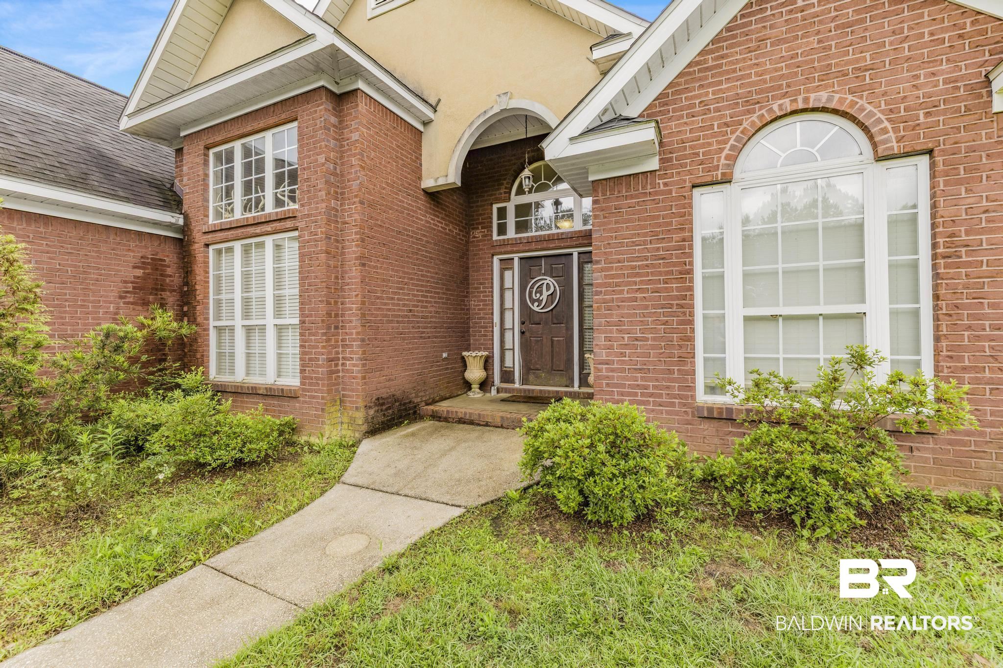 35814 Delvan Lane Bay Minette, AL 36507 - Photo 51 of 53 Brick exterior featuring a gabled roofline, arched portico, arched transom window, and white-framed multi-pane windows