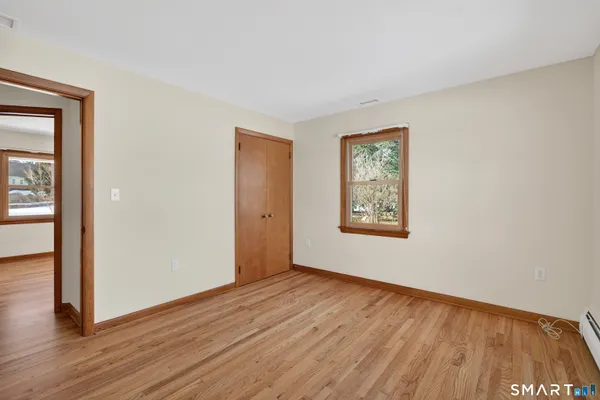 a view of an empty room with wooden floor and a window