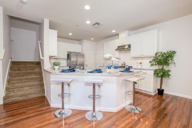 a kitchen with kitchen island granite countertop wooden floor cabinets and a sink