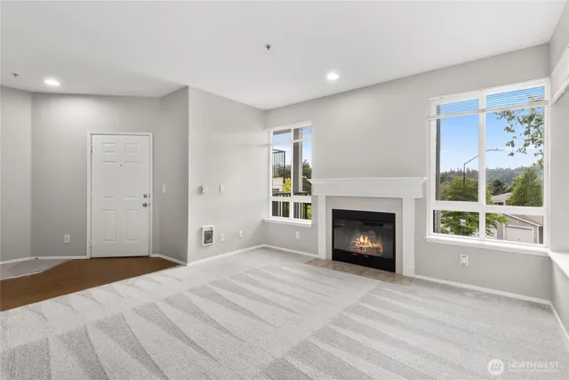 a view of a livingroom with a fireplace a ceiling fan and windows