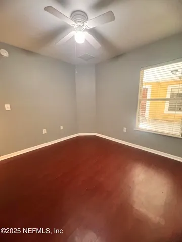 an empty room with a window and a ceiling fan
