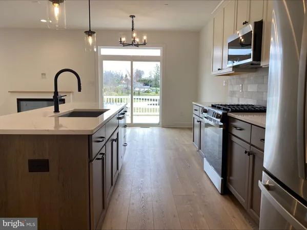 a kitchen with stainless steel appliances granite countertop a stove a sink a refrigerator and wooden floor