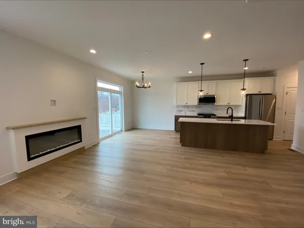 a view of kitchen with kitchen island stainless steel appliances a sink cabinets and wooden floor