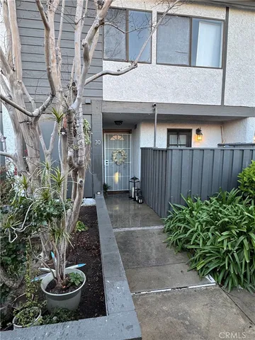a view of a house with plants and a fountain