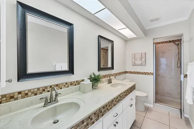 a bathroom with a granite countertop double vanity sink mirror and toilet