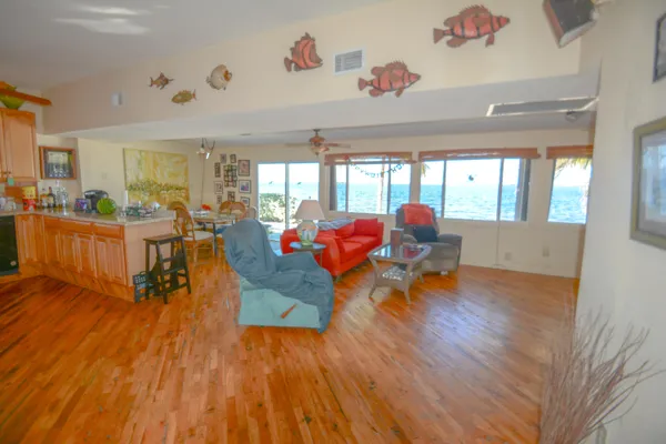 a kitchen with stainless steel appliances granite countertop a refrigerator a sink dishwasher a stove and a dining table with wooden floor