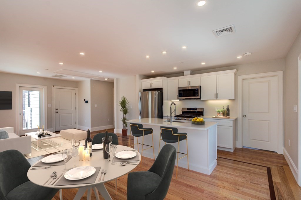 a kitchen with a dining table wooden floor and stainless steel appliances