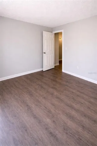 a view of an empty room with wooden floor and closet
