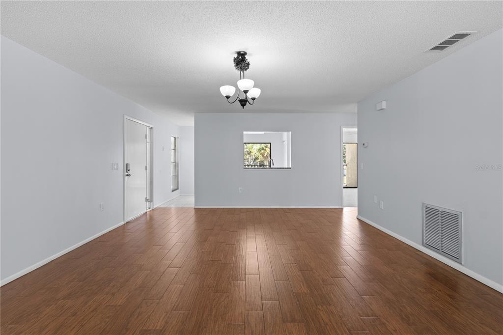 6110 Country Club Way, Unit 204 Sarasota, FL 34243 - Photo 15 of 66 an empty room with wooden floor chandelier and windows