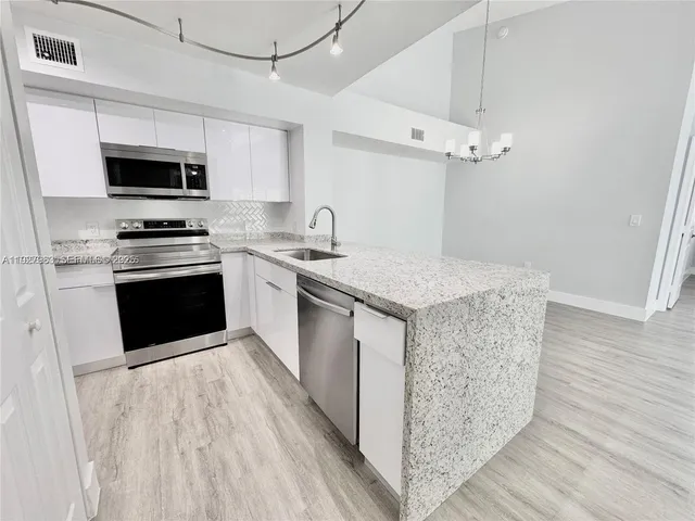 a kitchen with stainless steel appliances granite countertop a kitchen island a stove a sink and a microwave