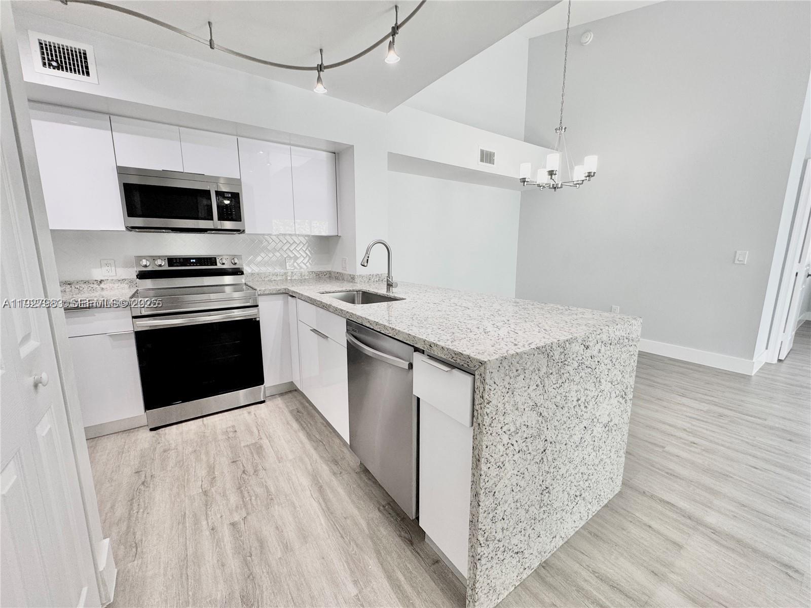 a kitchen with stainless steel appliances granite countertop a kitchen island a stove a sink and a microwave