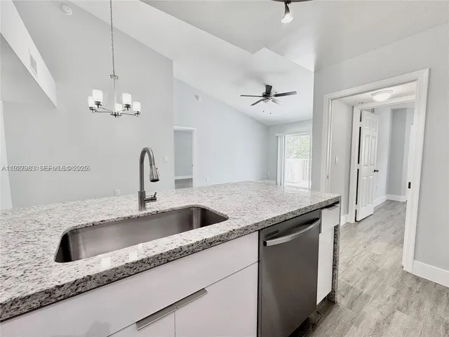a kitchen with granite countertop a sink and a refrigerator
