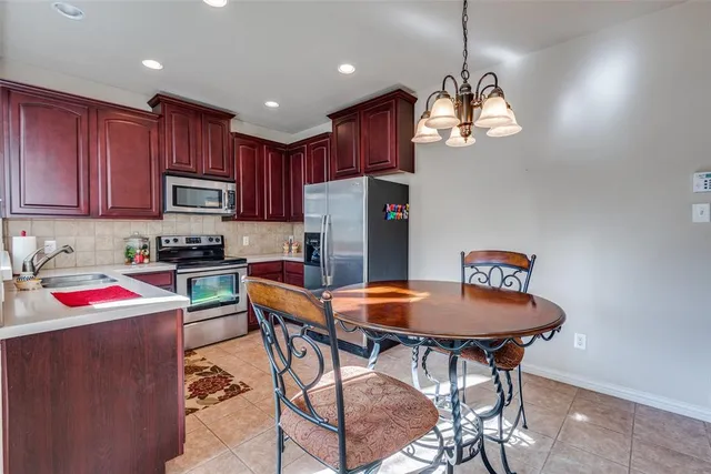 a kitchen with a dining table chairs refrigerator and microwave