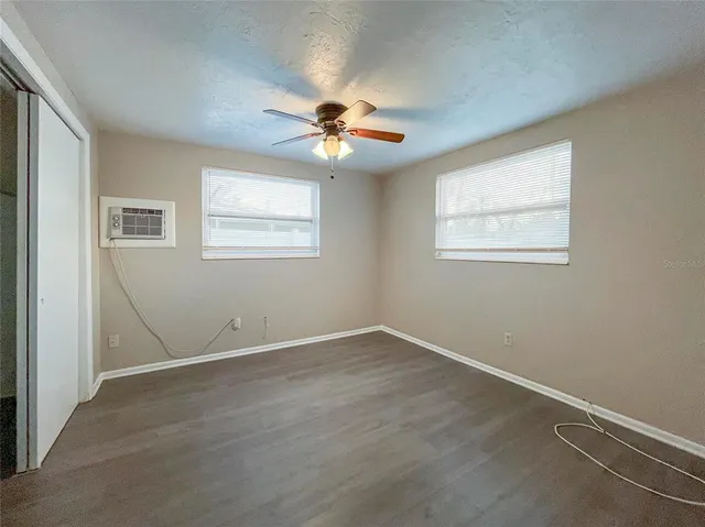 an empty room with windows and fan