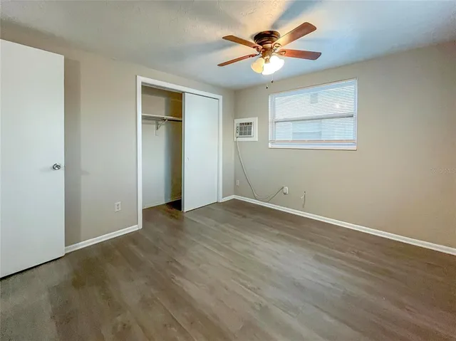 an empty room with wooden floor and a ceiling fan