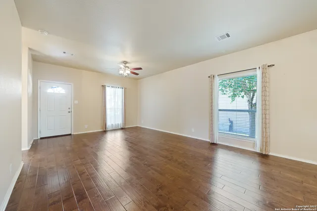an empty room with wooden floor cabinet and windows