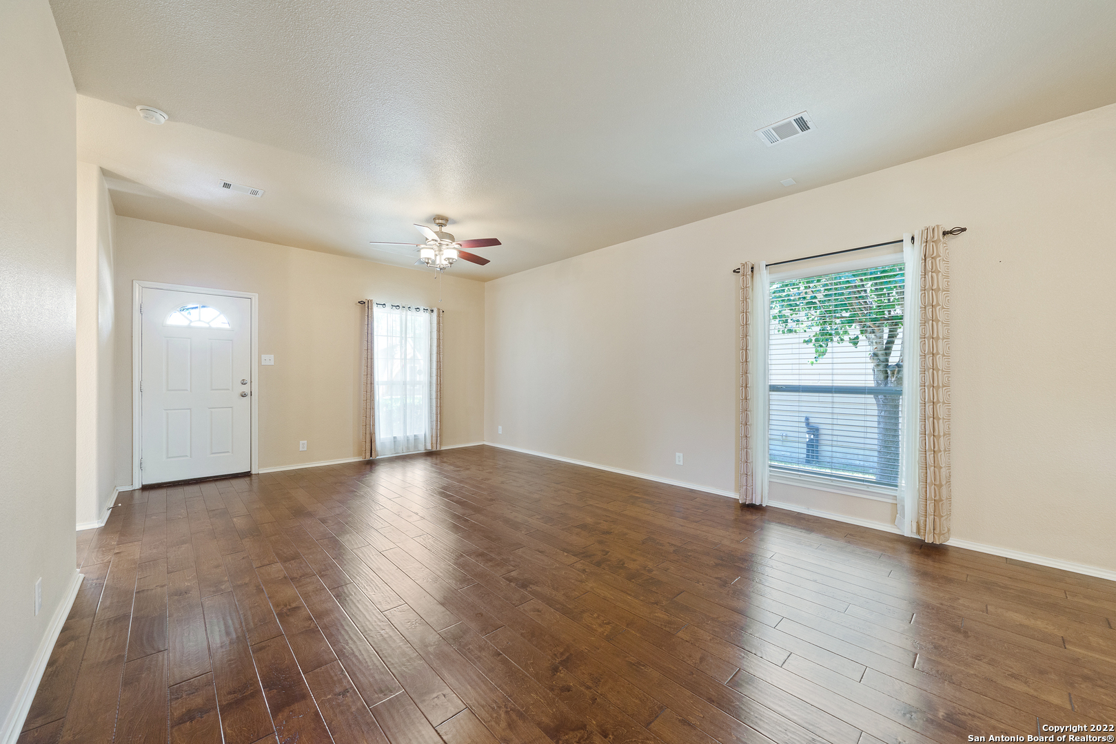 308 Rustic Trail Cibolo, TX 78108 - Photo 7 of 25 an empty room with wooden floor cabinet and windows