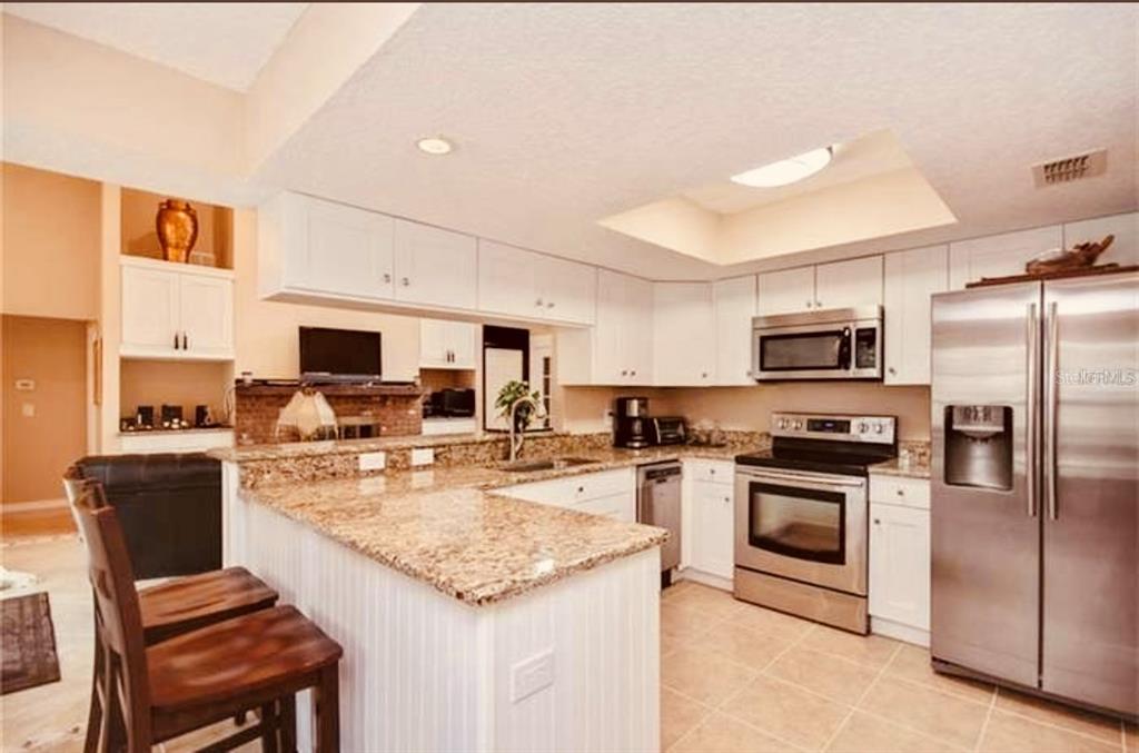 6850 Spring Rain Drive Orlando, FL 32819 - Photo 12 of 35 a kitchen with stainless steel appliances granite countertop a stove top oven a sink dishwasher a dining table and chairs with wooden floor