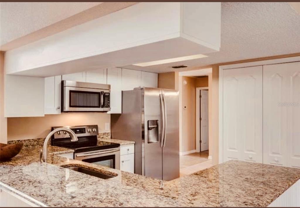 6850 Spring Rain Drive Orlando, FL 32819 - Photo 13 of 35 a kitchen with stainless steel appliances granite countertop a refrigerator a stove and a sink
