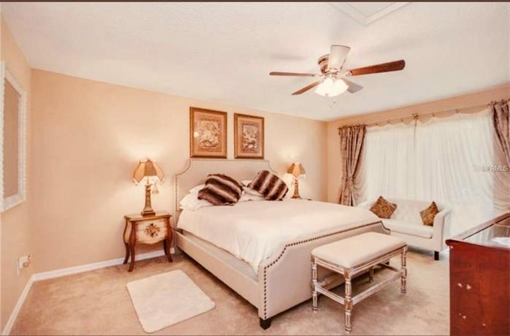 6850 Spring Rain Drive Orlando, FL 32819 - Photo 18 of 35 a bedroom with a bed and a chandelier