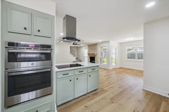 a kitchen with granite countertop white cabinets stainless steel appliances and wooden floor