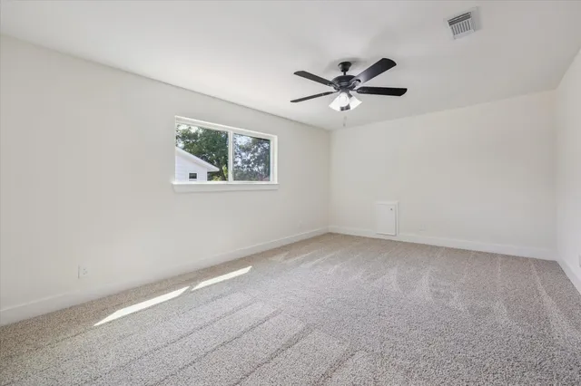 an empty room with a window and a fan