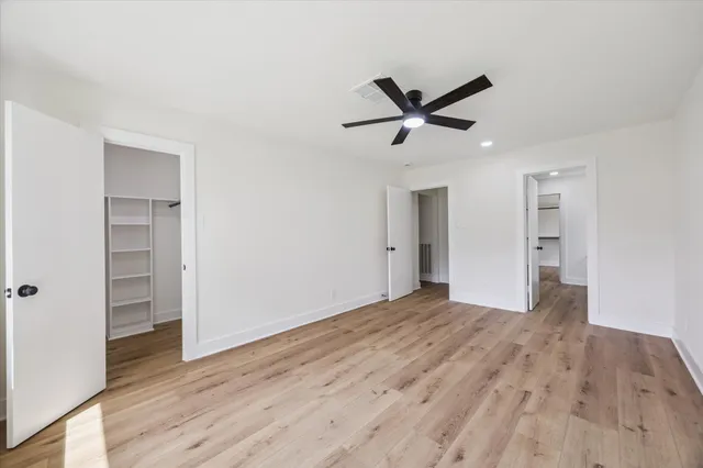 a view of empty room with wooden floor and ceiling fan