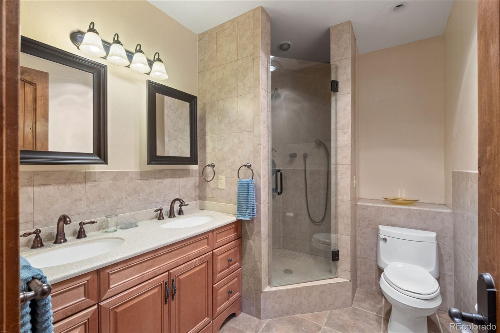 27659 Misty Road Golden, CO 80403 - Photo 37 of 50 a bathroom with a granite countertop sink a toilet a mirror and shower