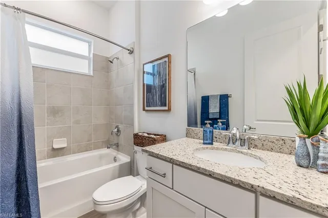 a bathroom with a granite countertop sink a mirror a bathtub and shower