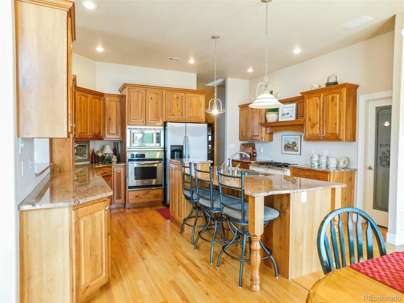 4351 Little Burnt Mill Road Pueblo, CO 81004 - Photo 7 of 45 a kitchen with stainless steel appliances kitchen island granite countertop a refrigerator a stove a sink dishwasher with a dining table and chairs with wooden floor