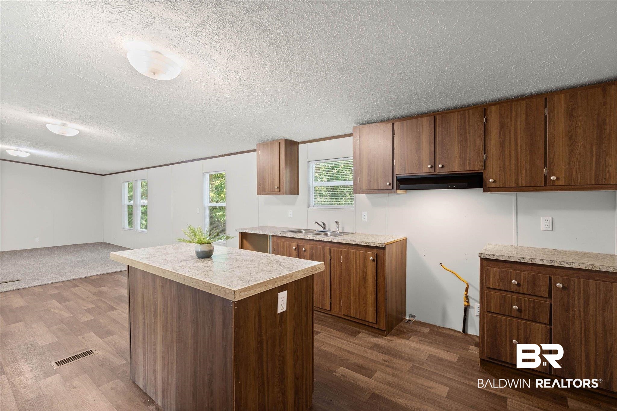25366 Pollard Road Daphne, AL 36526 - Photo 9 of 22 Spacious kitchen featuring wood-finish flooring, a central island with a light-toned countertop, and abundant wood-finish cabinetry