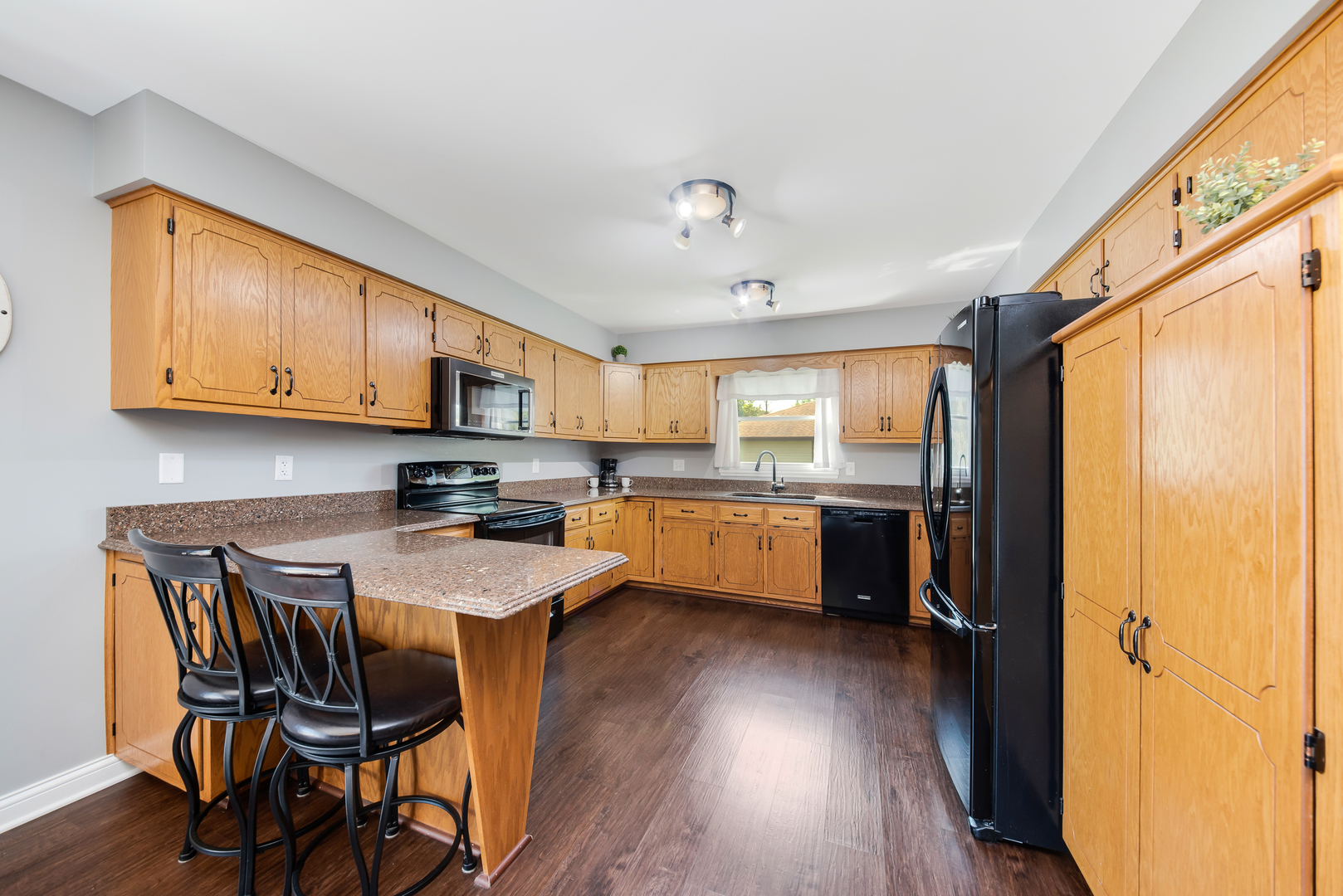 200 Beechwood Drive Minooka, IL 60447 - Photo 5 of 26 a kitchen with stainless steel appliances granite countertop wooden floors a dining table and chairs