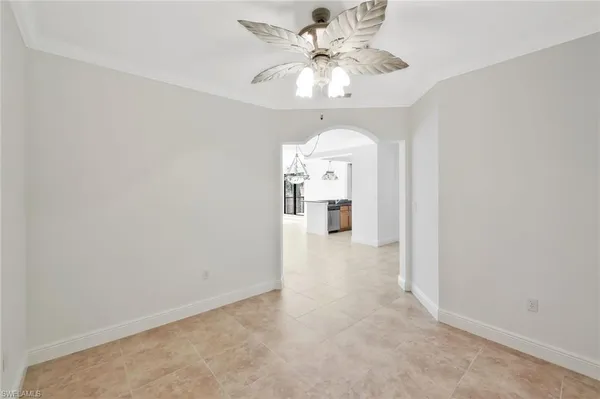 an empty room with a chandelier fan and windows