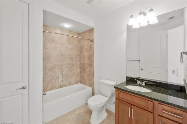 a bathroom with a granite countertop sink a toilet and bathtub