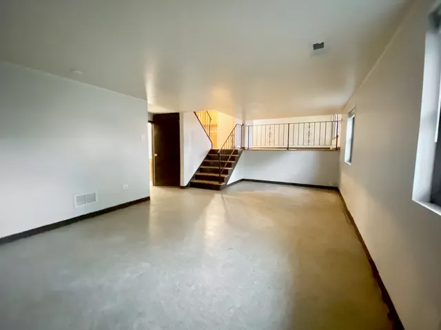 a view of an empty room with wooden floor and stairs
