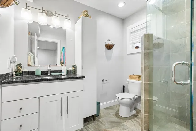 a bathroom with a granite countertop sink a toilet and shower