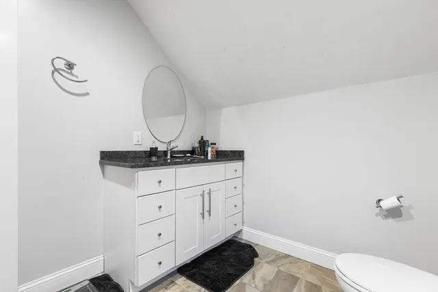 a bathroom with a granite countertop sink a toilet and a mirror