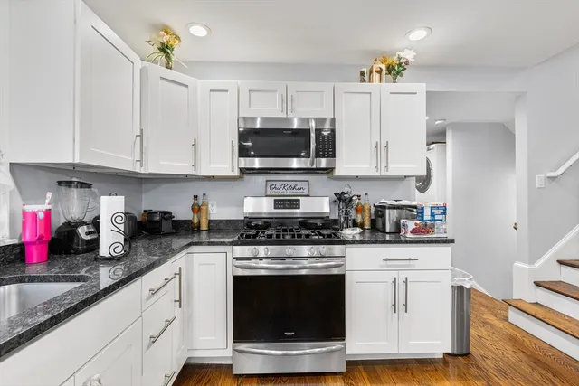 a kitchen with stainless steel appliances granite countertop a stove a sink and a white cabinets