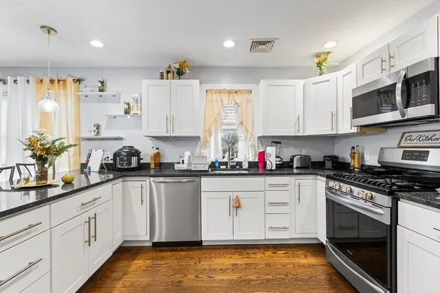 a kitchen with stainless steel appliances granite countertop a stove a sink and white cabinets