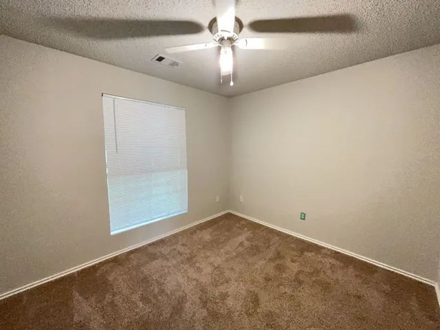 an empty room with a chandelier fan and windows